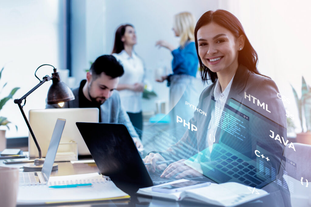 A woman focused on her laptop, surrounded by other people in a busy office setting on Dot-net-core development.