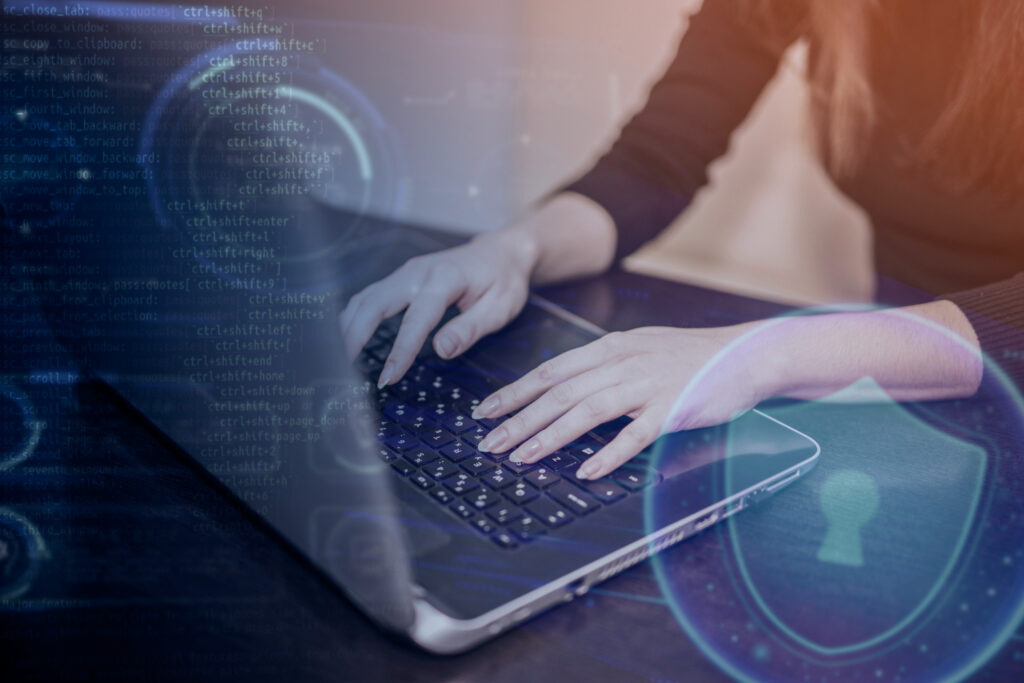 A woman typing on a laptop with a shield on the screen and IoT-AI development