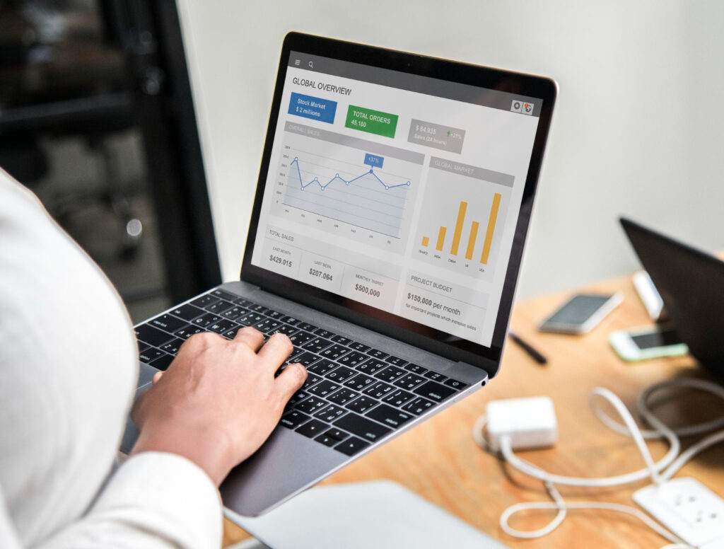 A person sitting at a desk using a laptop with a graph displayed on the screen and digital marketing services.